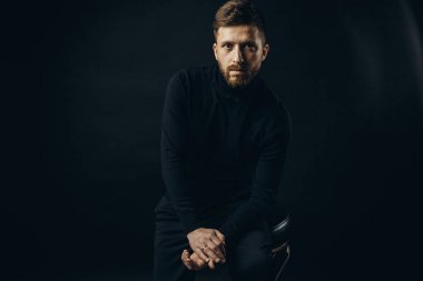 Siyah sandalye üzerinde poz içinde kendine güvenen adam