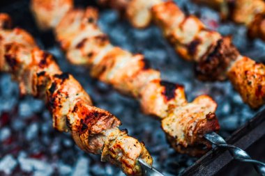 Metal şişte pişen ızgara kebap. Barbeküde pişmiş et. Geleneksel doğu yemeği, şiş kebap. Kömür ve alevler üzerine ızgara, piknik, sokak yemekleri