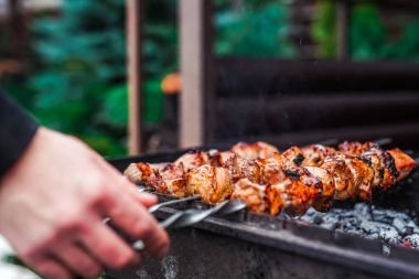 Metal şişte pişen ızgara kebap. Barbeküde pişmiş et. Geleneksel doğu yemeği, şiş kebap. Kömür ve alevler üzerine ızgara, piknik, sokak yemekleri
