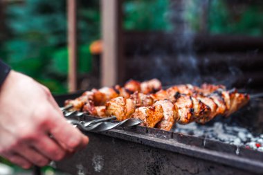 Metal şişte pişen ızgara kebap. Barbeküde pişmiş et. Geleneksel doğu yemeği, şiş kebap. Kömür ve alevler üzerine ızgara, piknik, sokak yemekleri