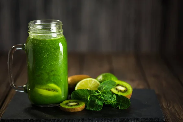 Misturado smoothie verde com ingredientes na placa de pedra, madeira — Fotografia de Stock