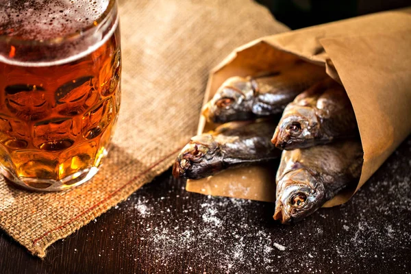 Сушеная рыба и винтажный стакан пива на черном фоне — стоковое фото