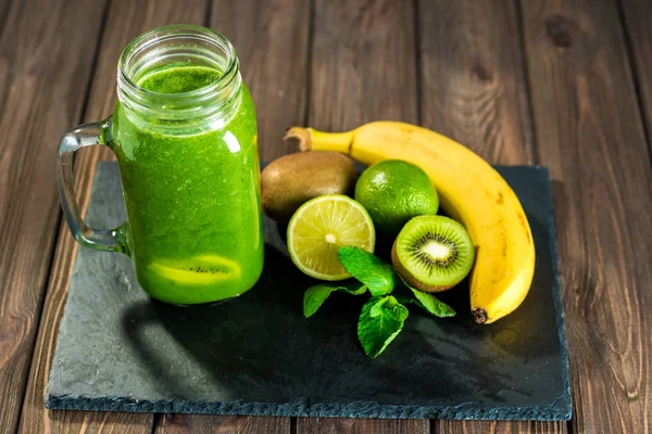 Blended green smoothie with ingredients on the stone wooden tabl — Stock Photo, Image