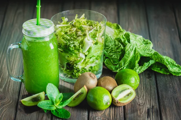 Licuado batido verde con ingredientes en la mesa de madera selectiv —  Fotos de Stock