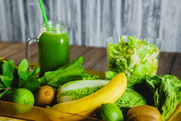 Blended green smoothie with ingredients on wooden table selectiv — Stock Photo, Image