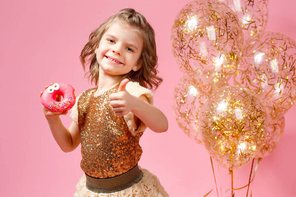 Девушка держит пончик и показывает пальцем вверх
