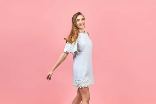 Menina bonita vestindo vestido branco e posando no fundo rosa . — Fotografia de Stock