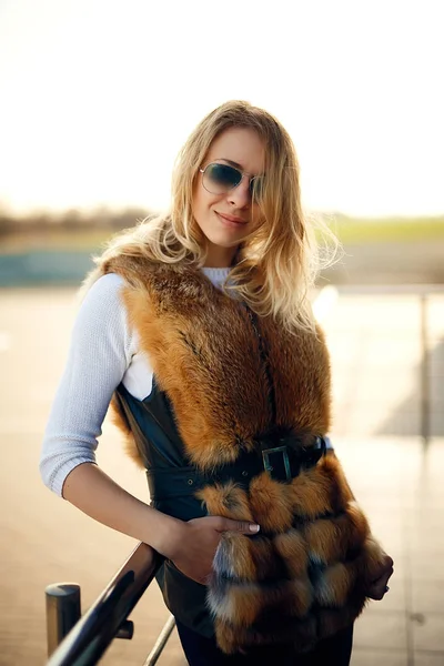 Hermosa joven al aire libre en un chaleco de piel y gafas de sol —  Fotos de Stock