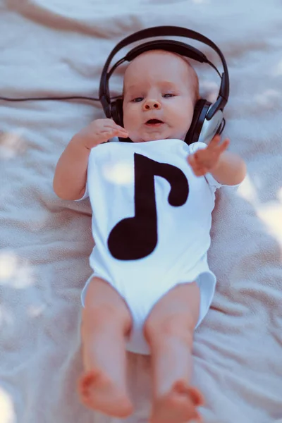 Bebé en auriculares grandes acostado en la cama — Foto de Stock