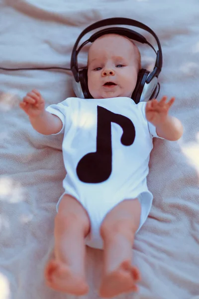 Bebé en auriculares grandes acostado en la cama — Foto de Stock