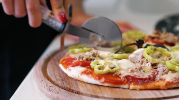 Het meisje snijdt de pizza in de keuken — Stockvideo