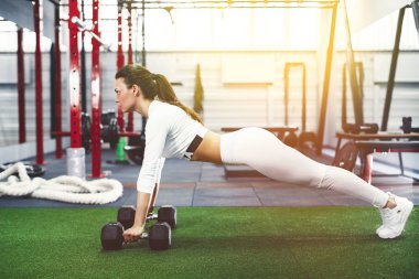 Çekici genç kadın spor yaparken kalas egzersizi yapıyor.