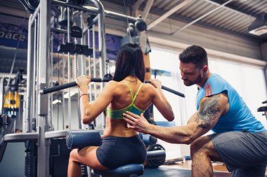 Sportif kız Yardımı salonunda kişisel onu antrenman ör ile ağırlık egzersizleri yapıyor.