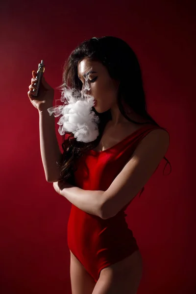 Jovem mulher sexy é vaping. Uma nuvem de vapor. Estúdio tiro . — Fotografia de Stock
