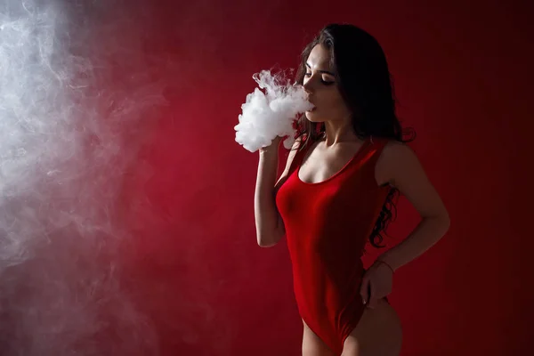 Young sexy woman is vaping. A cloud of vapor. Studio shooting. — Stock Photo, Image