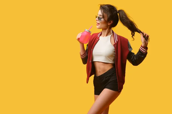 Young woman with drinking jar on yellow background — Stock Photo, Image