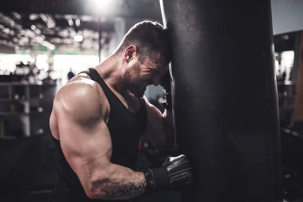 Manlig boxerträning med boxningssäck i mörk sporthall. — Stockfoto