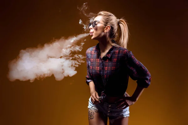 Woman standing and vaping in studio — Stock Photo, Image