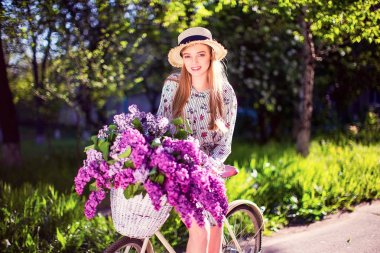 vintage Bisiklet ve çiçeklerle şehir arka planda açık güneş ışığı üzerinde güzel genç kız.