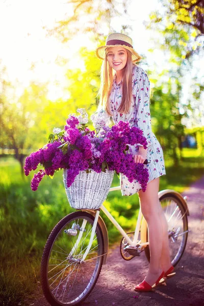 Piękna młoda dziewczyna z rocznika rowerów i kwiaty na tle miasta w zewnątrz światło słoneczne. — Zdjęcie stockowe
