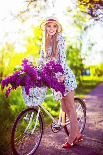 Красивая молодая девушка с винтажным велосипедом и цветами на фоне города на солнечном воздухе . — стоковое фото
