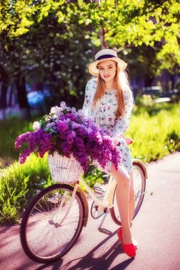 vintage Bisiklet ve çiçeklerle şehir arka planda açık güneş ışığı üzerinde güzel genç kız.