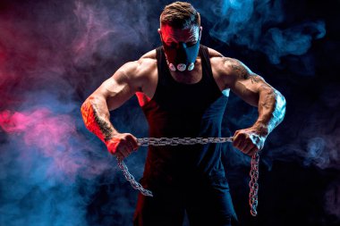 Kaslı sporcu metal zincir yırtılma portresi. Siyah arka plan ile duman