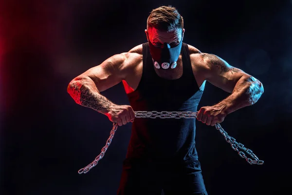 金属チェーンを引き裂く筋肉スポーツマンの肖像画。黒の背景 — ストック写真