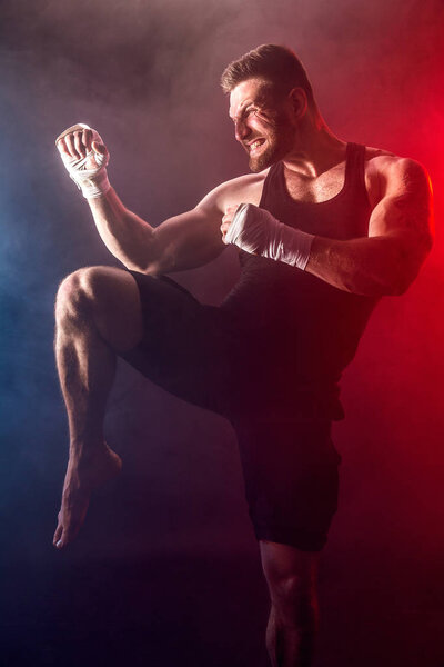 Sportsman muay thai boxer fighting on black background with smoke.