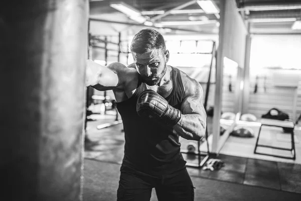 Entrenamiento de boxeador masculino con saco de boxeo en pabellón deportivo oscuro. —  Fotos de Stock