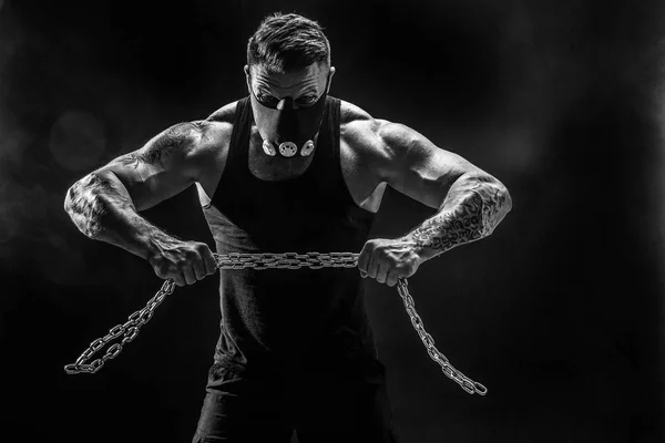 Ritratto di sportivo muscoloso che strappa catena metallica. Fondo nero con fumo — Foto Stock