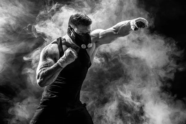 Fuerte atleta masculino en una máscara de entrenamiento negro sobre un fondo negro — Foto de Stock