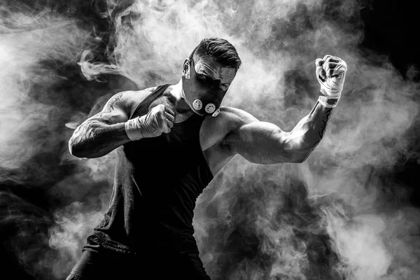 Fuerte atleta masculino en una máscara de entrenamiento negro sobre un fondo negro —  Fotos de Stock