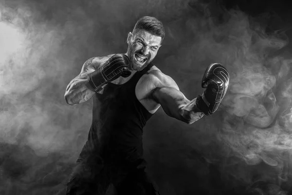 Sportsman muay thai boxer fighting on black background with smoke.
