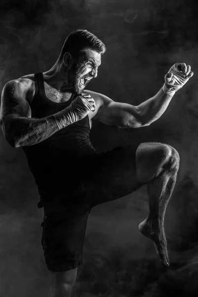 Sportsman muay thai boxer fighting on black background with smoke.