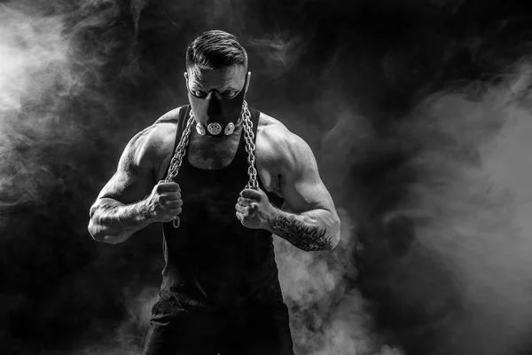 金属チェーンと筋肉スポーツマンの肖像画。煙が黒の背景 — ストック写真