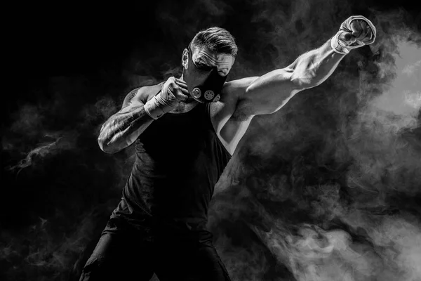 Atleta masculino forte em uma máscara de treinamento preto em um fundo preto — Fotografia de Stock