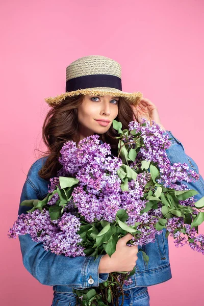 Gelukkig lachende vrouw geniet van geur van boeket lila bloemen over kleurrijke blauwe achtergrond — Stockfoto