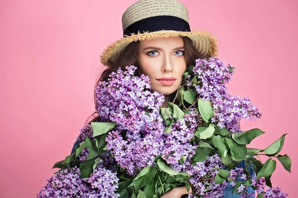 Gelukkig lachende vrouw geniet van geur van boeket lila bloemen over kleurrijke blauwe achtergrond — Stockfoto