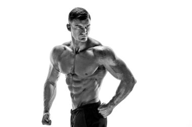 Kaslı süper yüksek seviye yakışıklı bir adam beyaz arka grubunda poz veriyor.