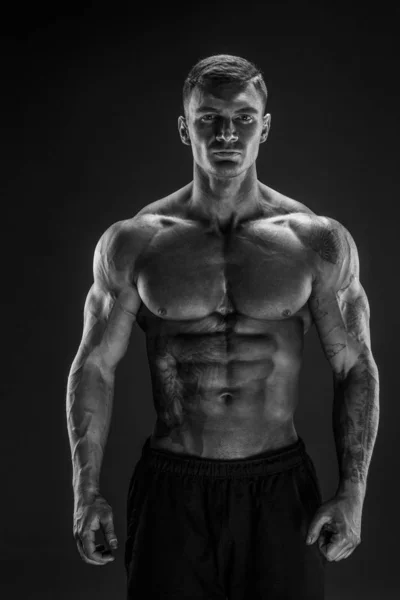 Bodybuilder poserar. Fitness muskulös man på mörk bakgrund. — Stockfoto