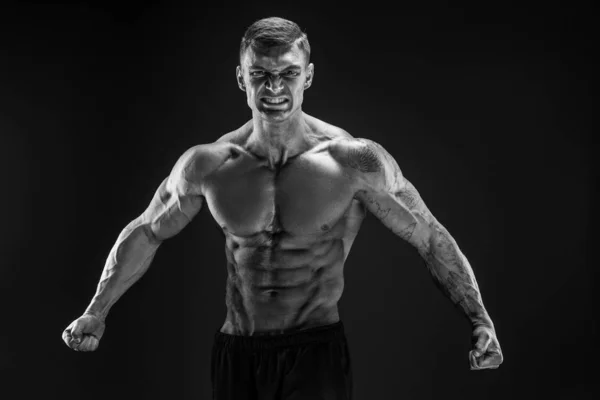 Bodybuilder posiert. Fitnessmuskulöser Mann auf dunklem Hintergrund. Gebrüll — Stockfoto