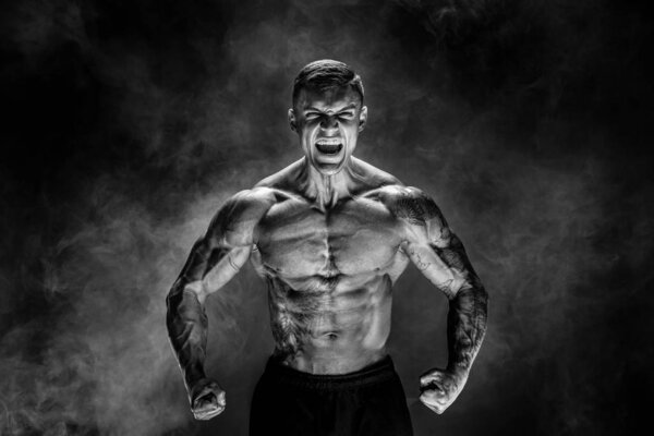 Bodybuilder posing. Fitness muscled man on dark background. Roar
