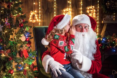 Küçük kız Noel Baba 'nın kulağına fısıldıyor. Bir sır söylemek. Kazanmak istediğin hediyeyi ortaya çıkarmak. Yıl boyunca nasıl davrandığından bahsediyordu.