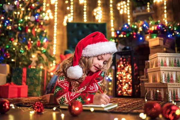 Rolig tjej i santa hatt skriver brev till santa — Stockfoto