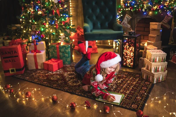 Funny girl in Santa hat écrit une lettre au Père Noël — Photo
