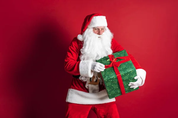 Foto einer Art Weihnachtsmann, der ein Weihnachtsgeschenk macht und in die Kamera schaut — Stockfoto