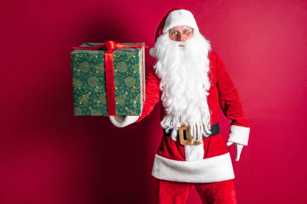 Foto einer Art Weihnachtsmann, der ein Weihnachtsgeschenk macht und in die Kamera schaut — Stockfoto