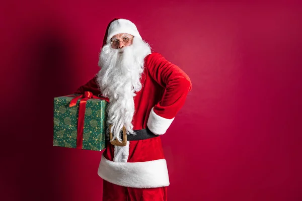Foto de tipo Santa Claus dando regalo de Navidad y mirando a la cámara —  Fotos de Stock