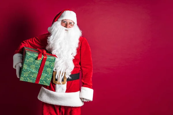 Foto einer Art Weihnachtsmann, der ein Weihnachtsgeschenk macht und in die Kamera schaut — Stockfoto